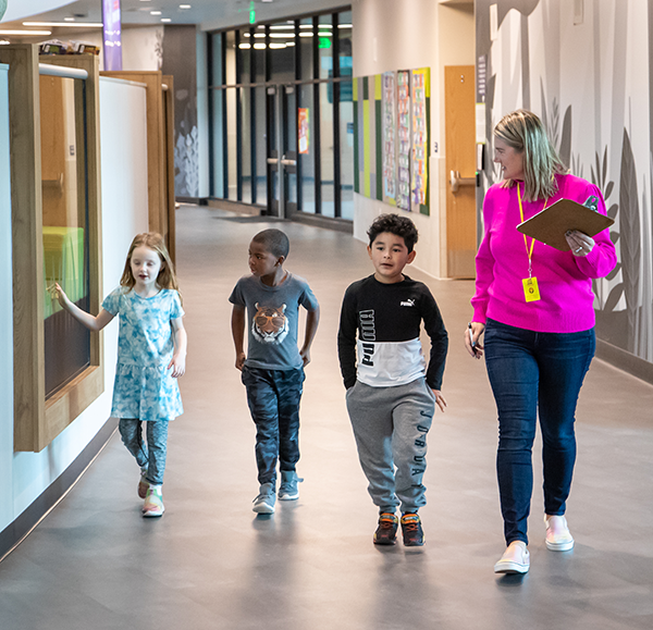 Photo: teacher walking with elementary kids in hallway at school